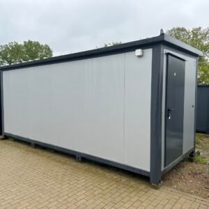 Außenansicht des Duschcontainers mit heller Wandverkleidung, dunklem Rahmen und Tür in der Stirnwand
