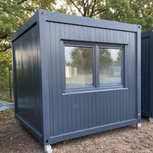 Anthrazitfarbener Bürocontainer 3,00 x 3,00 m mit breitem Doppelfenster, aufgeständert auf Bodenplatten