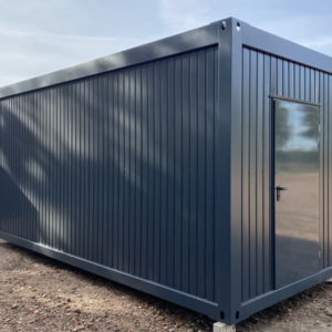 Bürocontainer 6,00 x 2,44 m in Anthrazit mit verglaster Stirnwandtür, aufgestellt auf einem Kiesplatz