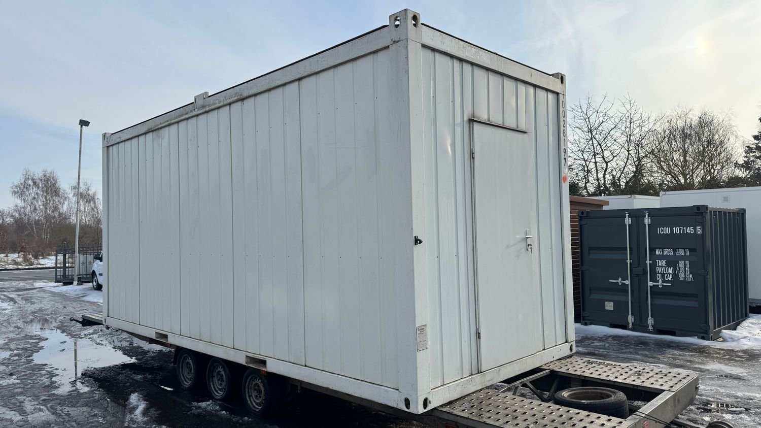 Seitenansicht mit Stirnwandtür des Mannschaftscontainers 20’ auf dem Anhänger im Hof