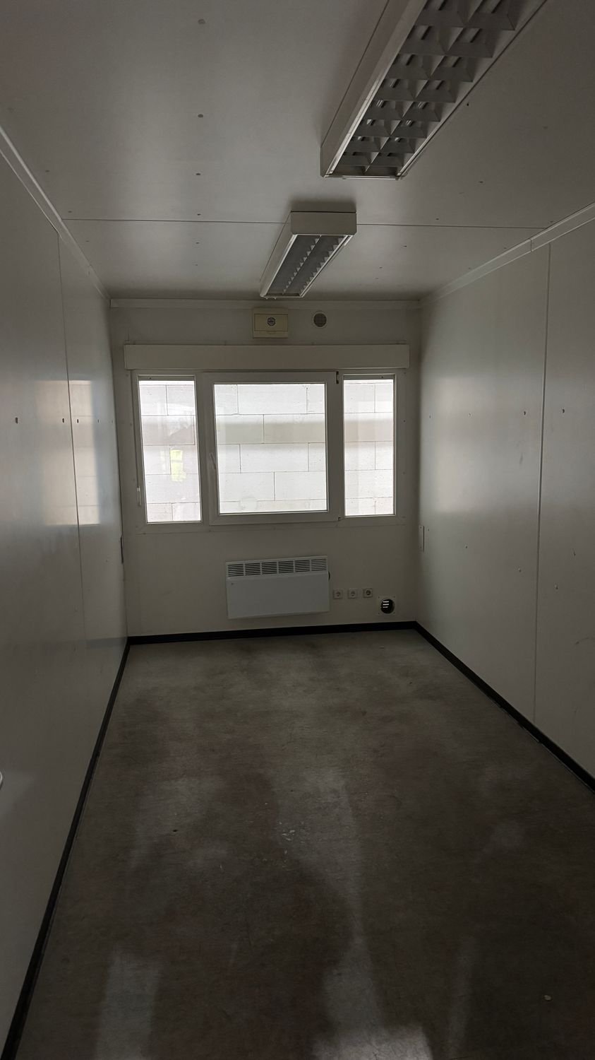 Rollladenkasten über dem Fensterband, Wandkonvektor und Rasterleuchten im Innenraum