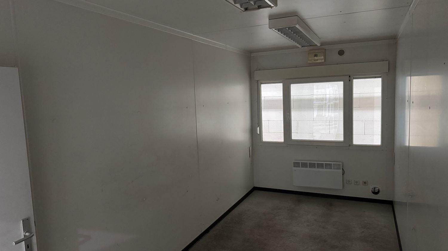 Querformataufnahme des Innenraums mit Fenster, Elektroheizung und Steckdosenblock
