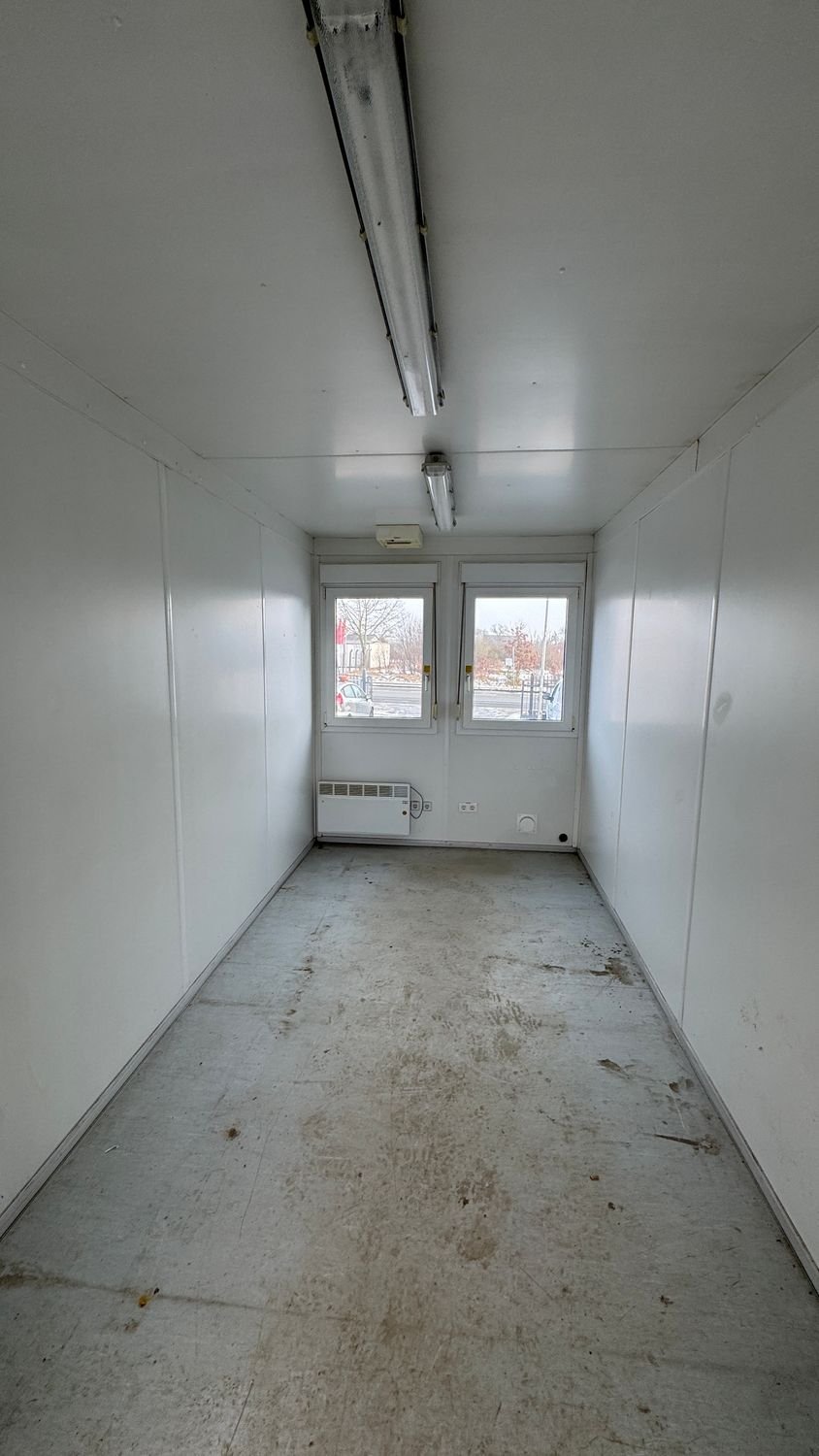 Innenansicht mit Doppelfenster, Elektroheizkörper, Steckdosen und Leuchtstoffröhren an der Decke