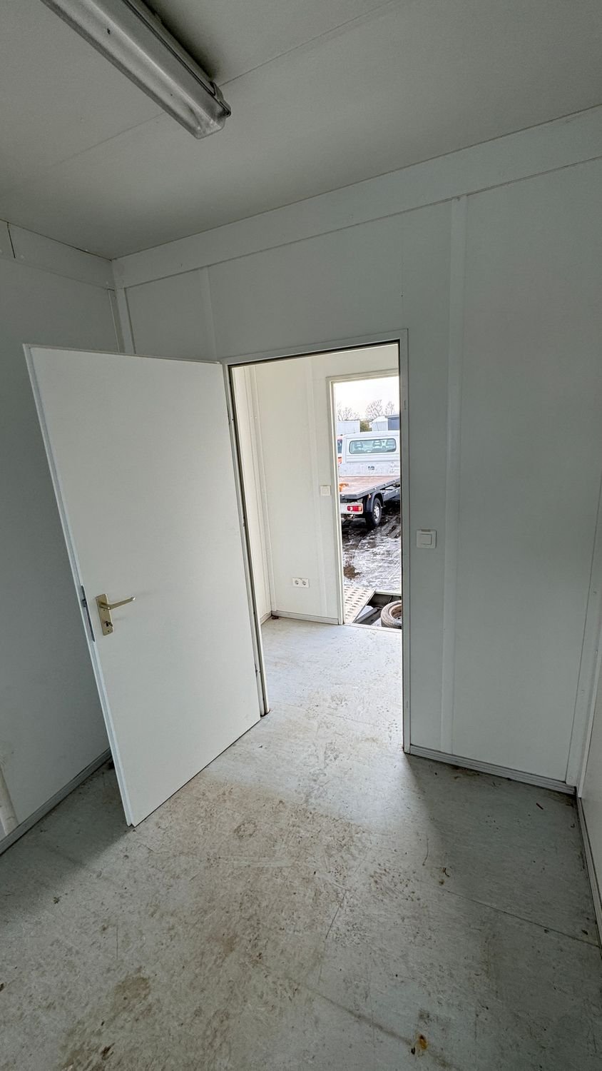 Vorraum mit geöffneter Zwischentür und Ausgang, Steckdose und Lichtschalter an der Wand