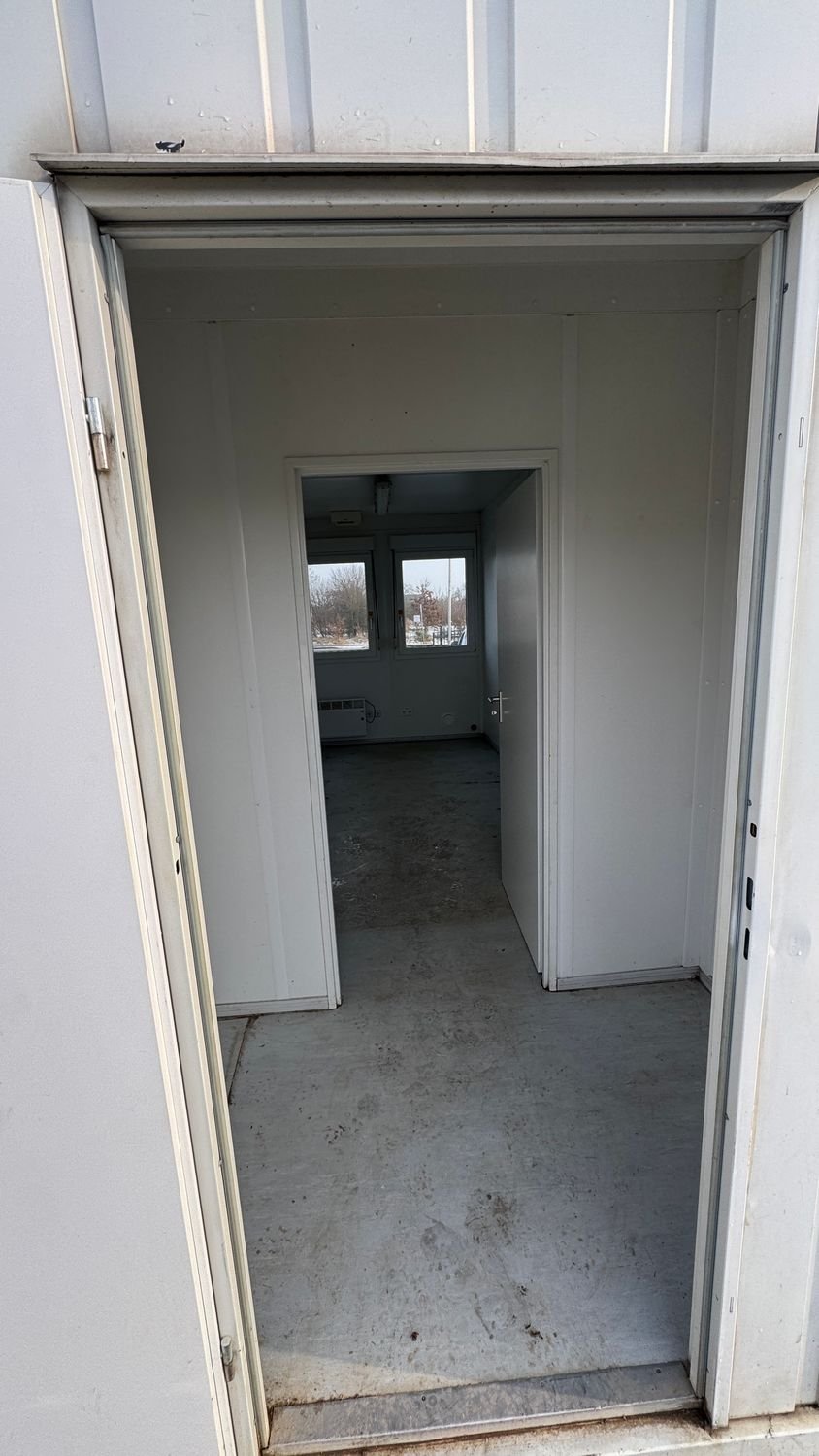 Durch die offene Eingangstür in den Flur und weiter in den Raum mit Fenster und Heizung