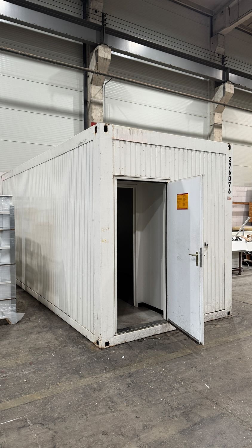 Weiterer weißer Raumcontainer mit geöffneter Stirnwandtür, aufgestellt in einer Halle