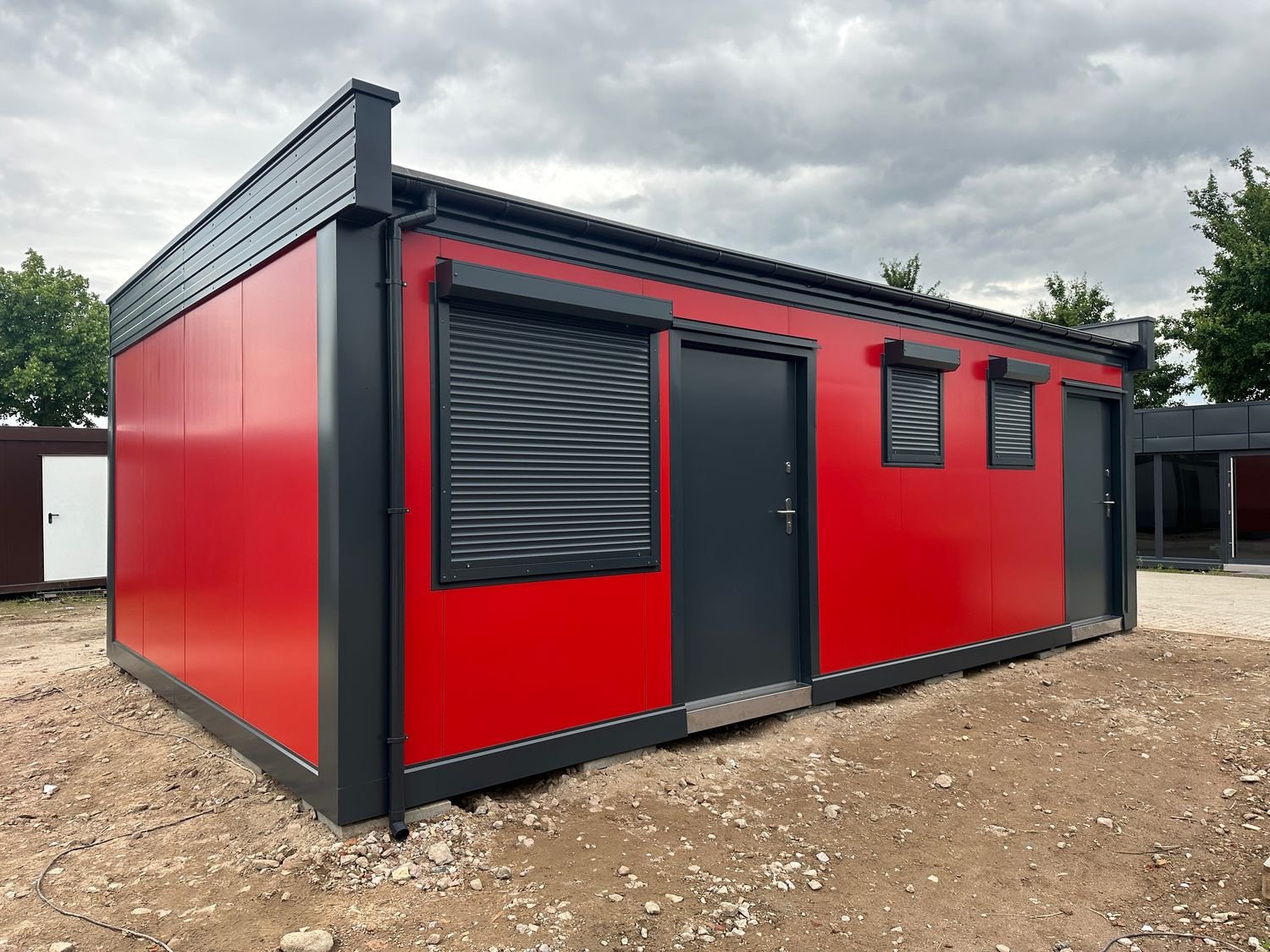 Rückseite mit Rollladenklappe, zwei anthrazitfarbenen Türen und kleinen Fenstern des Imbisscontainers
