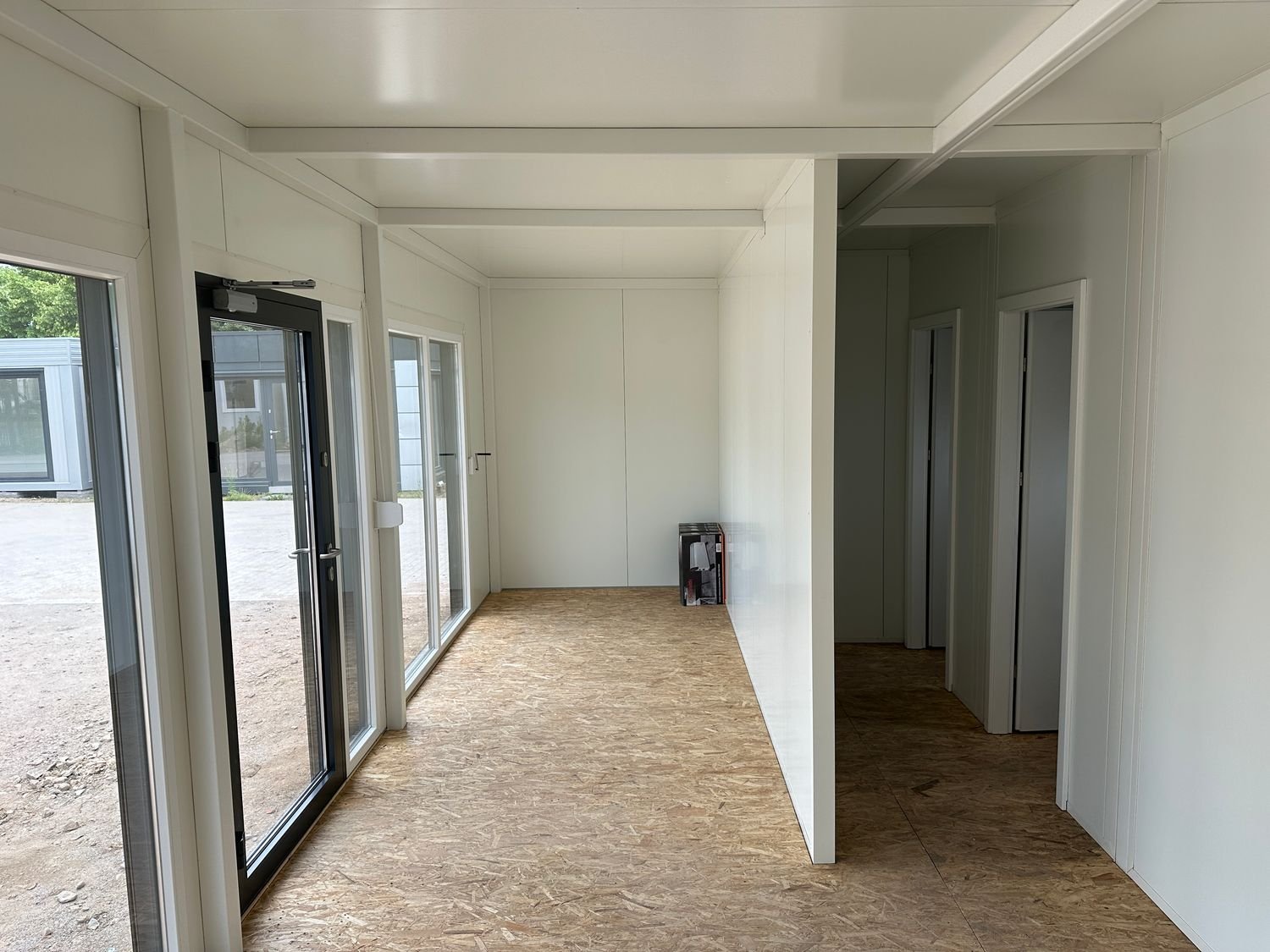Blick durch den leeren Verkaufsraum auf die Trennwände und zwei Innentüren des Imbisscontainers