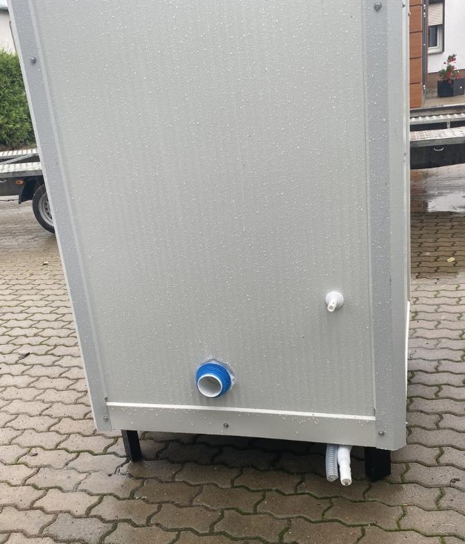 Detailaufnahme der Rückwand mit blauem Wasseranschluss, Ablaufstutzen und Standfüßen