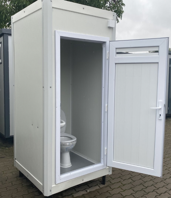Schrägansicht des Sanitärcontainers mit aufgeschwenkter Tür samt Lüftungsgitter und WC