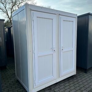 Schrägansicht des Sanitärcontainers mit zwei geschlossenen weißen Türen auf Pflasterfläche