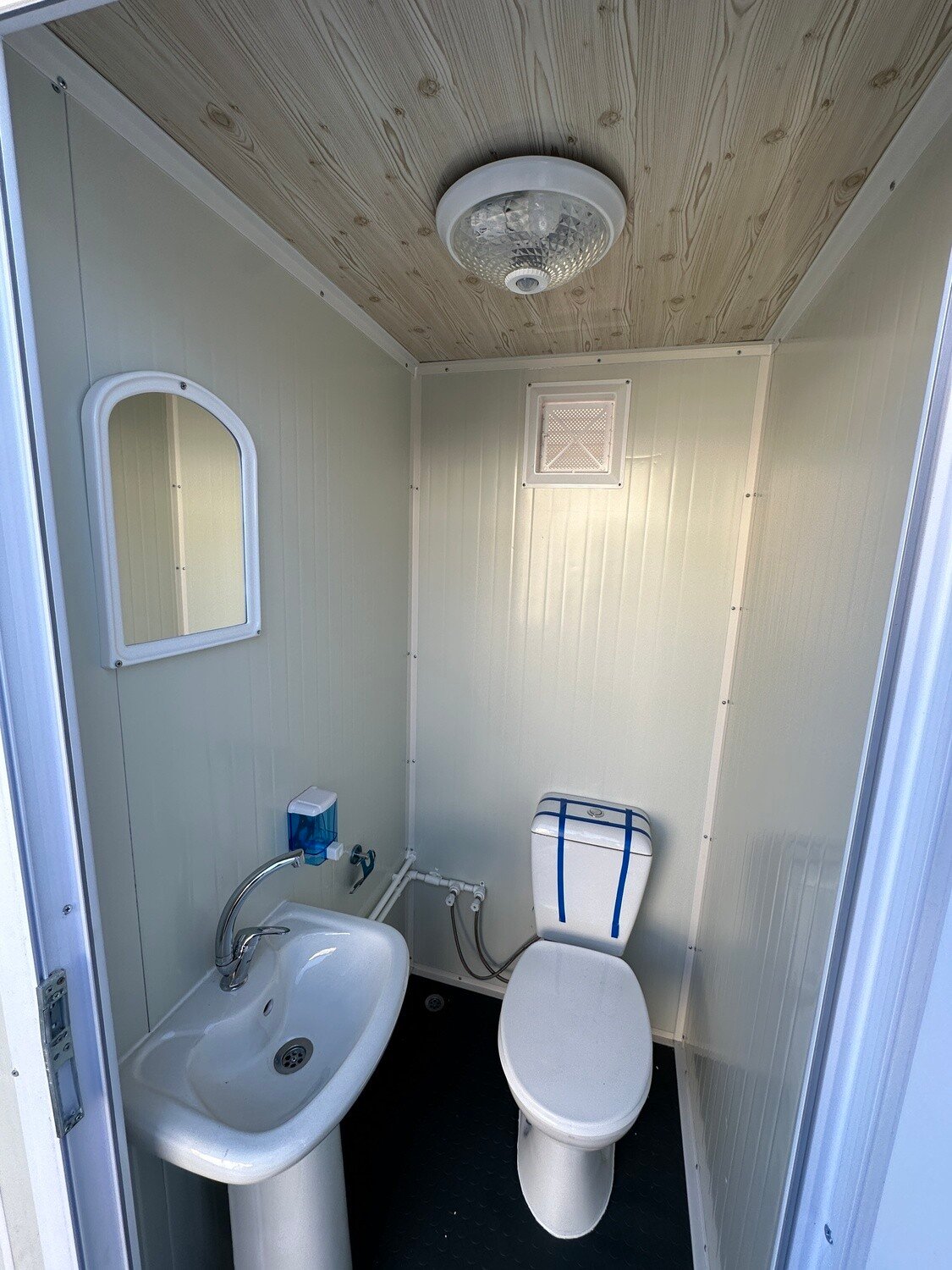 Innenansicht des Sanitärcontainers 1,30 x 2,05 m mit WC, Waschbecken, Spiegel und Seifenspender