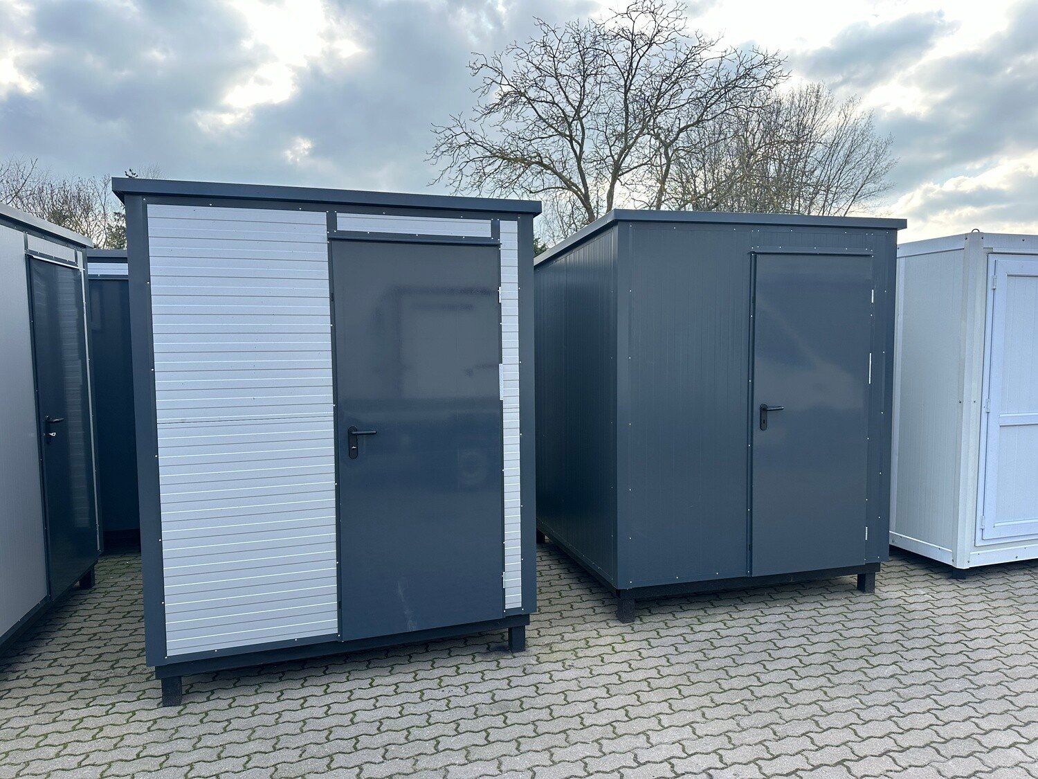 Zwei Sanitärcontainer 2,00 x 2,00 m nebeneinander, einer hell verkleidet, einer ganz in Anthrazit