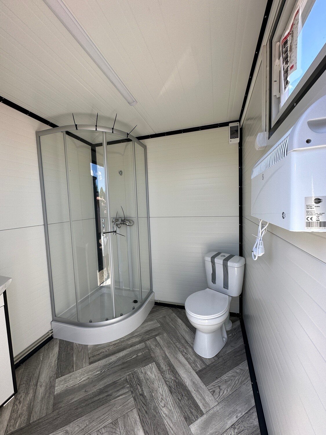 Innenansicht mit Rundduschkabine, WC und Wandheizgerät im Sanitärcontainer 2,00 x 2,00 m