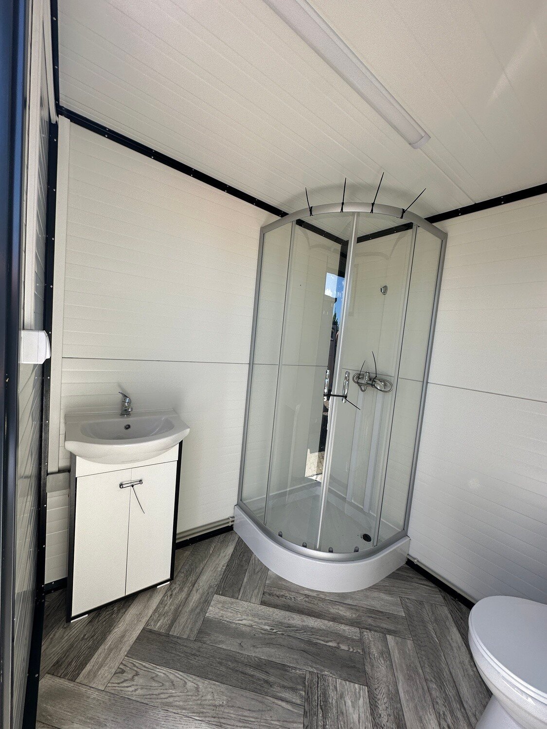 Waschtisch mit Unterschrank neben der Duschkabine im Sanitärcontainer 2,00 x 2,00 m