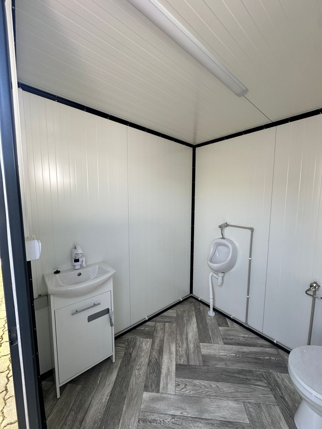 Waschtisch mit Unterschrank, Urinal und Deckenleuchte im Sanitärcontainer 2,00 x 2,00 m