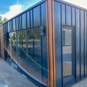 Außenansicht des Tiny House 10,00 x 3,00 m mit anthrazitfarbener Profilfassade, Holzleisten und Glasschiebetür