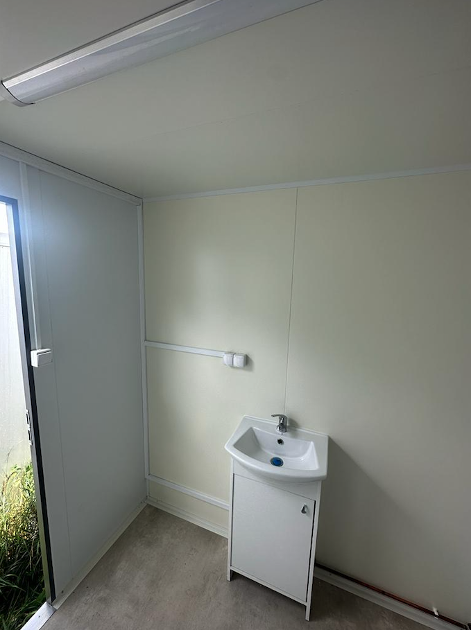 Waschtisch mit Handtuchhalter und Papierrollenhalter neben der offenen Tür des WC-Anhängers